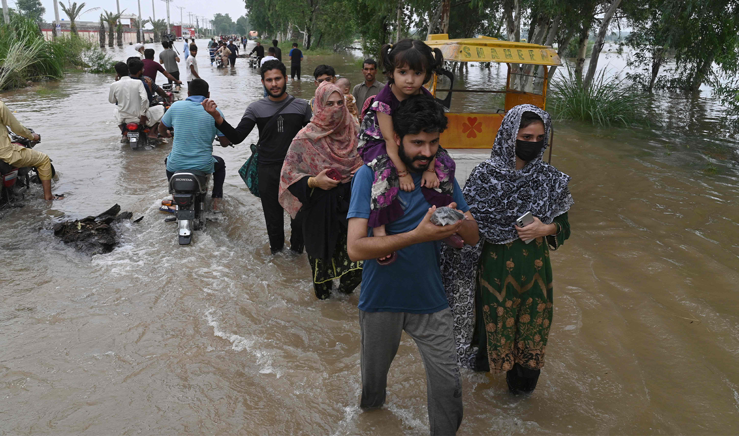 A family and others wade through the flooded area of Narowal, a town of Punjab province, on August 27,2025. Pakistan has been battered by a brutal monsoon season this year, with landslides and floods triggered by torrential rain killing more than 800 people since June. (AFP)