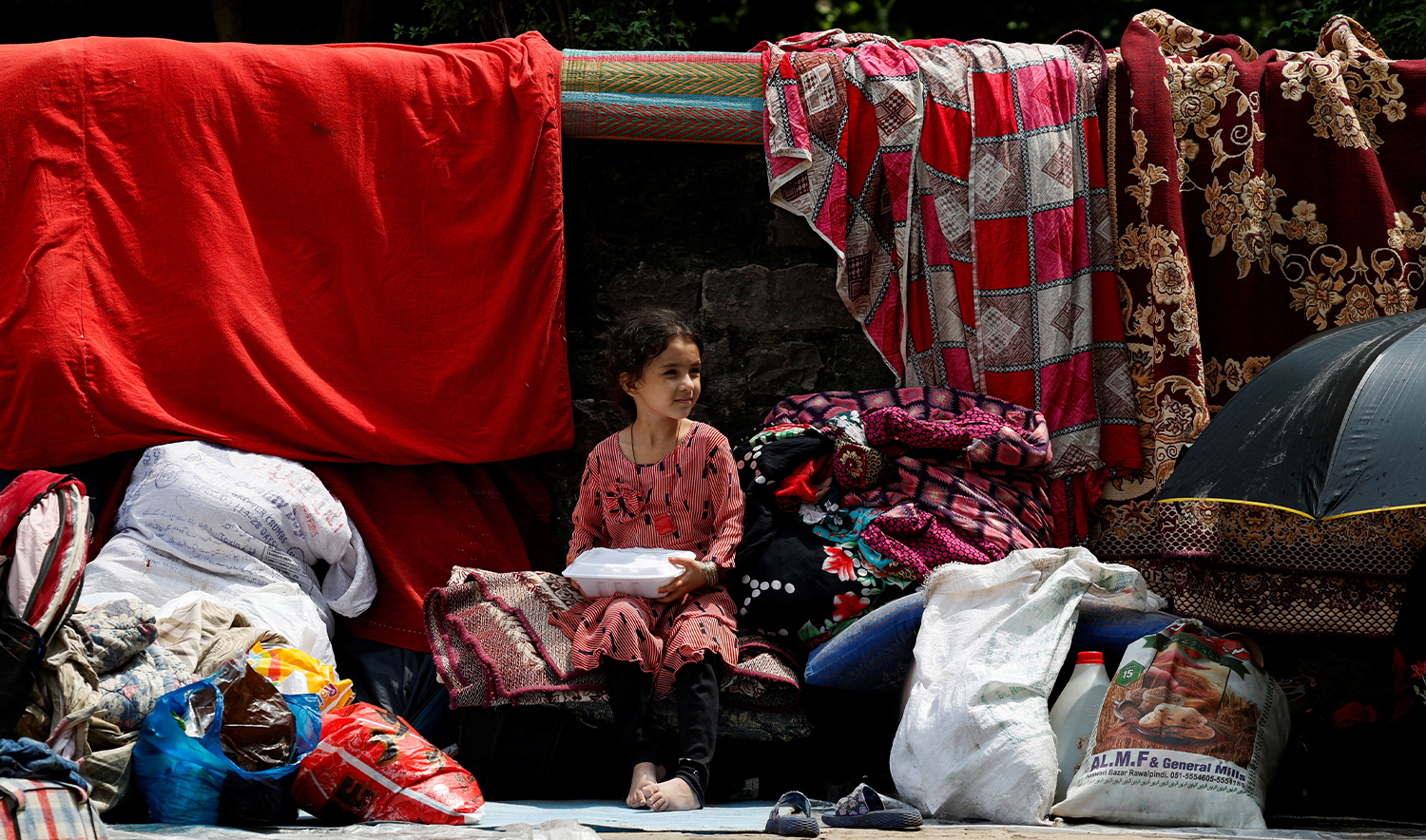 Rehana, 7, an Afghan citizen, sits with her family's belongings while taking shelter at a public park along with others after they were evicted, as Pakistan has started to deport documented Afghan refugees ahead of its deadline for them to leave, in Islamabad, Pakistan, on August 15, 2025. (REUTERS/File)