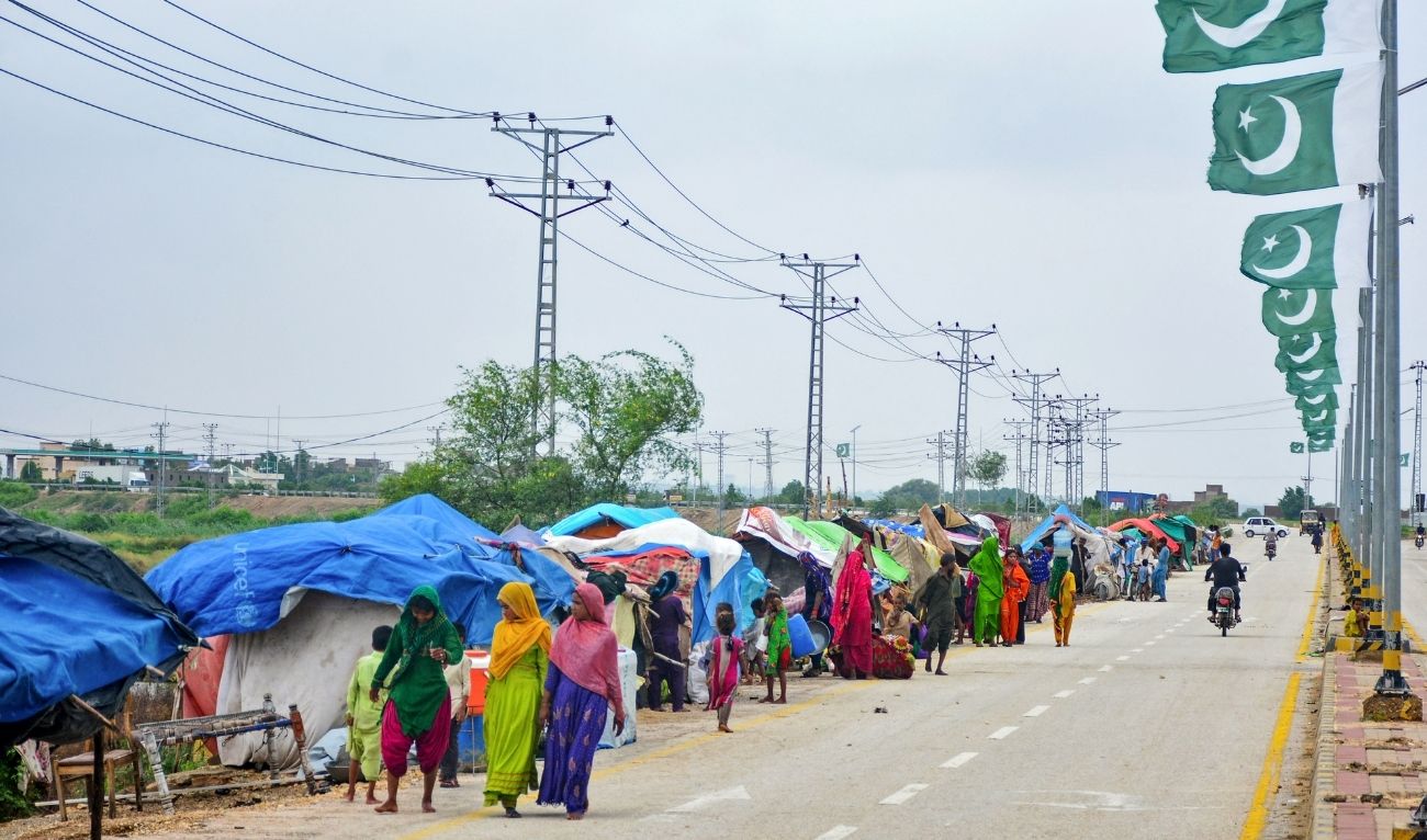Flood-affected people walk past their make-shift tents along a roadside after heavy monsoon rains in Hyderabad, Sindh province on August 30, 2024. (AFP/ file)