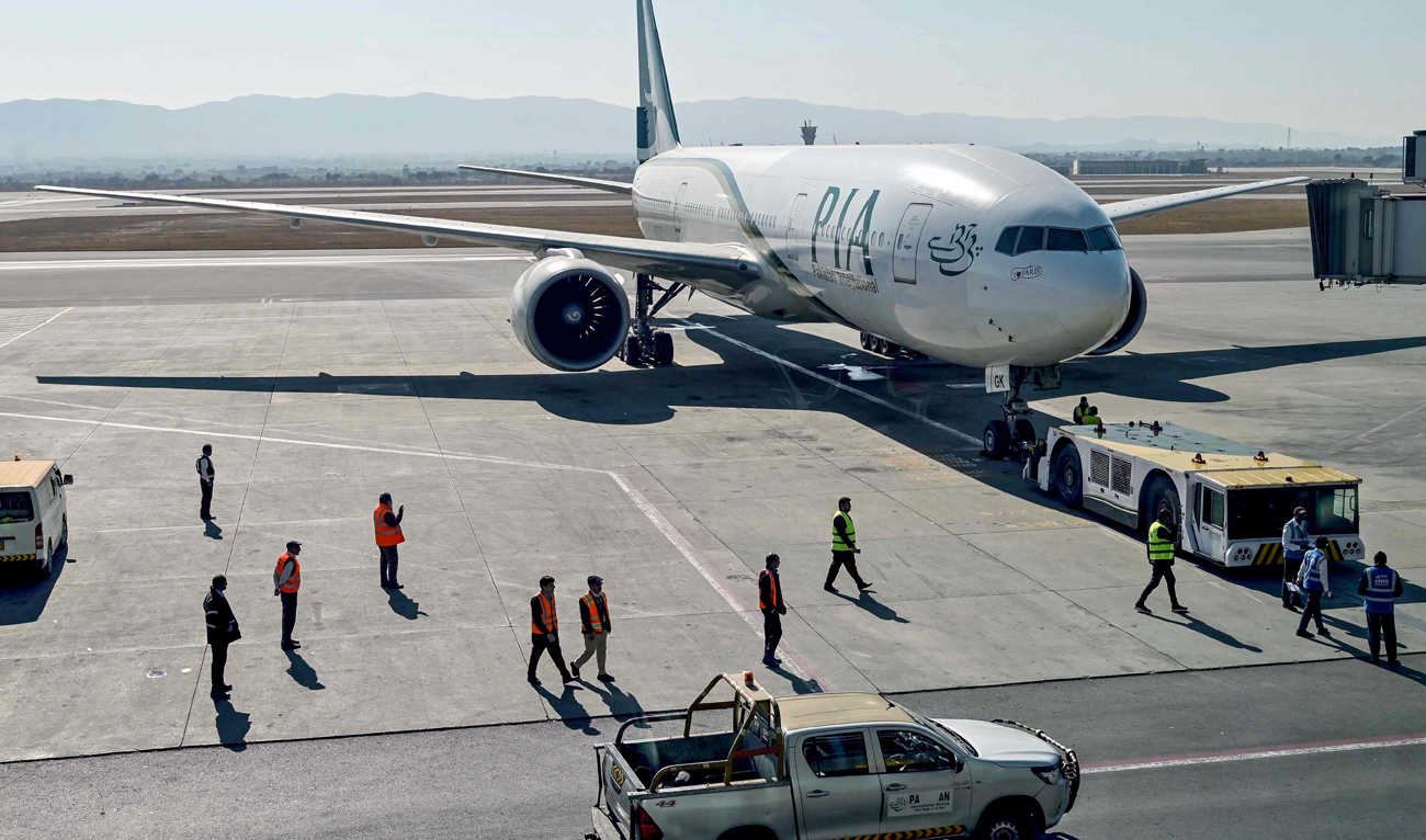 Ground staff stand next to the Pakistan International Airline (PIA) aircraft at the Islamabad International Airport on January 10, 2025. (AFP/File)