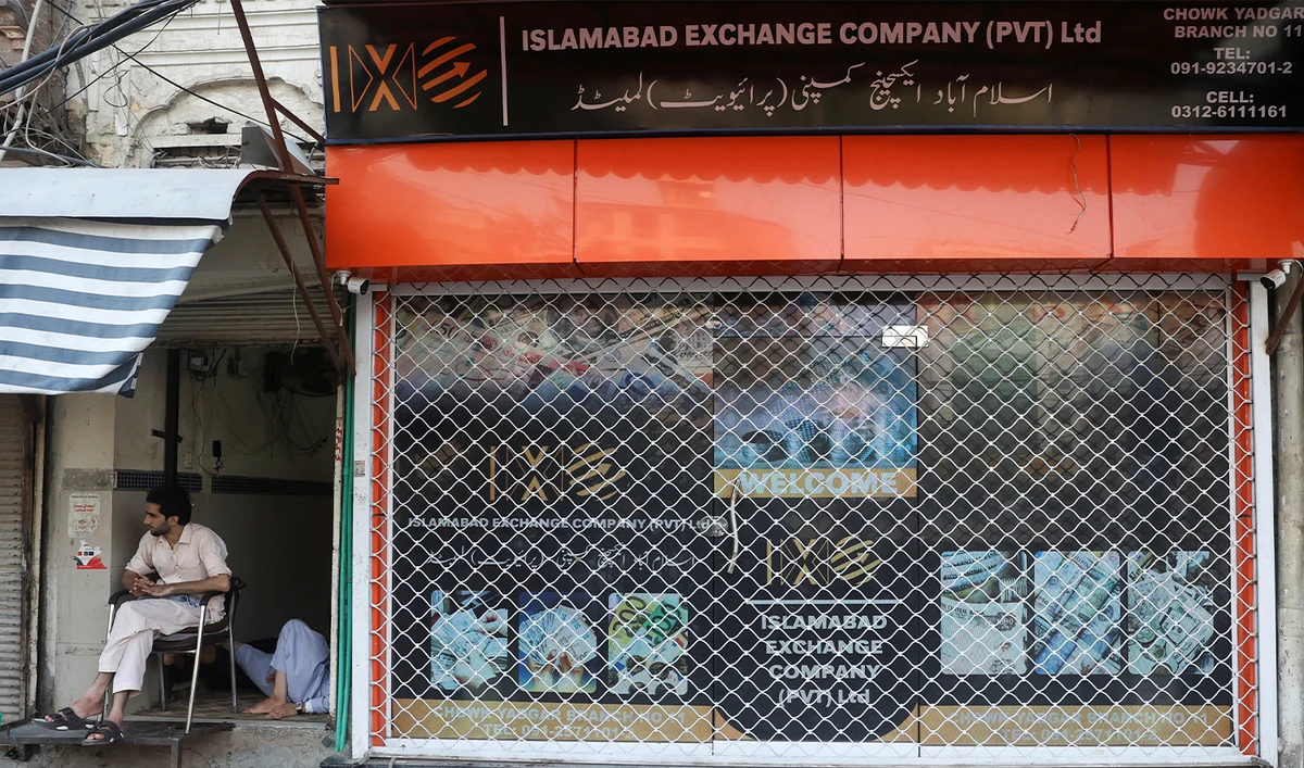 A man sits beside a closed currency exchange shop at a market in Peshawar, Pakistan, on July 29, 2025. (REUTERS/File)