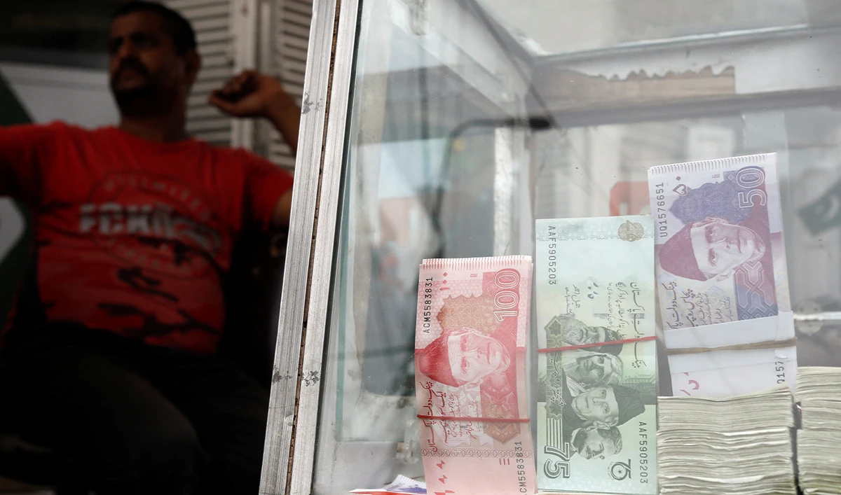 A money changer sits with a showcase, displaying Pakistan's banknotes, along a road in Karachi, Pakistan, on September 12, 2023. (REUTERS/File)