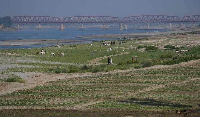 People walk next to a cultivated land on the dry riverbed of the Indus River in Hyderabad, Pakistan on April 25, 2025. (REUTERS/File)