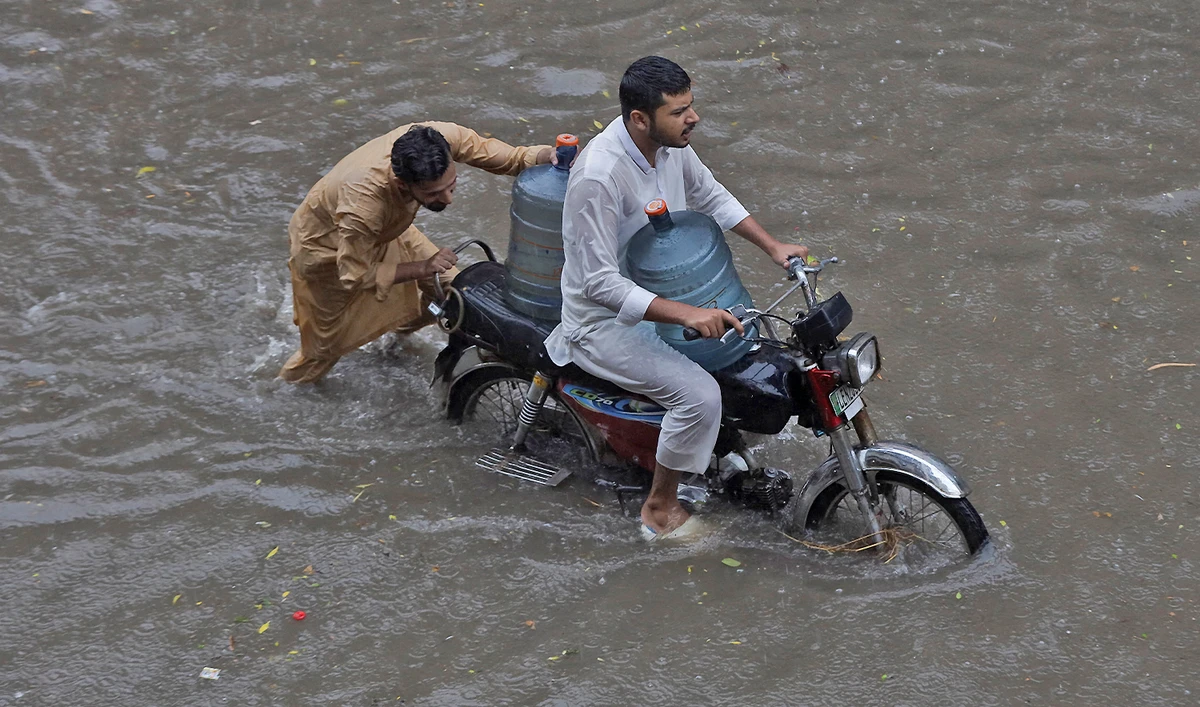 Men transport water bottles on motorbike through a flooded street amid downpour in Lahore, Pakistan on August 9, 2025. (REUTERS/File)