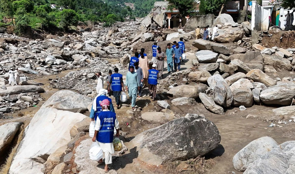 In this aerial picture, volunteers carry aid for residents, after flash floods hit Buner district in northern Pakistan's mountainous Khyber Pakhtunkhwa province on August 18, 2025. (AFP)