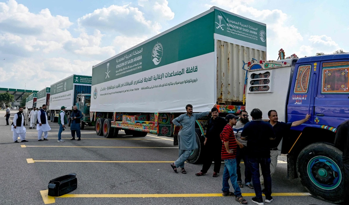 Men stand near trucks carrying relief aid donated by the Saudi Arabian government for flood victims, in Islamabad in August 20, 2025. (AFP)