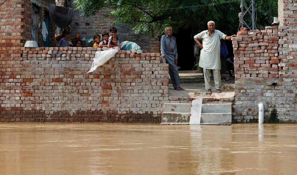 Residents stand at their house, amid flood due to the monsoon rains and rising water level of the Sutlej River, in Hakuwala village near the Pakistan-India border in Kasur district of the Punjab province, Pakistan, on August 23, 2025. (REUTERS)