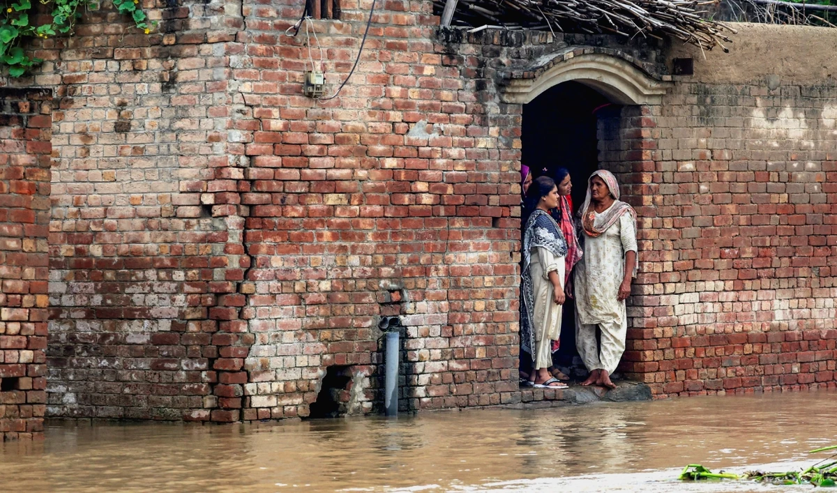 Residents stand at the entrance of a house on a flooded road, caused by monsoon rains and the rising water level of the Sutlej River, in Hakuwala village near the Pakistan-India border in Kasur district of Punjab province, Pakistan, on August 24, 2025. (REUTERS)