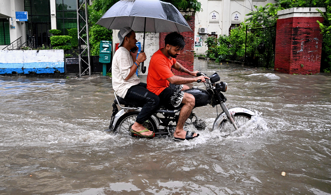 Commuters ride through flooded road amid heavy rain in Lahore on August 30, 2025. (AFP)