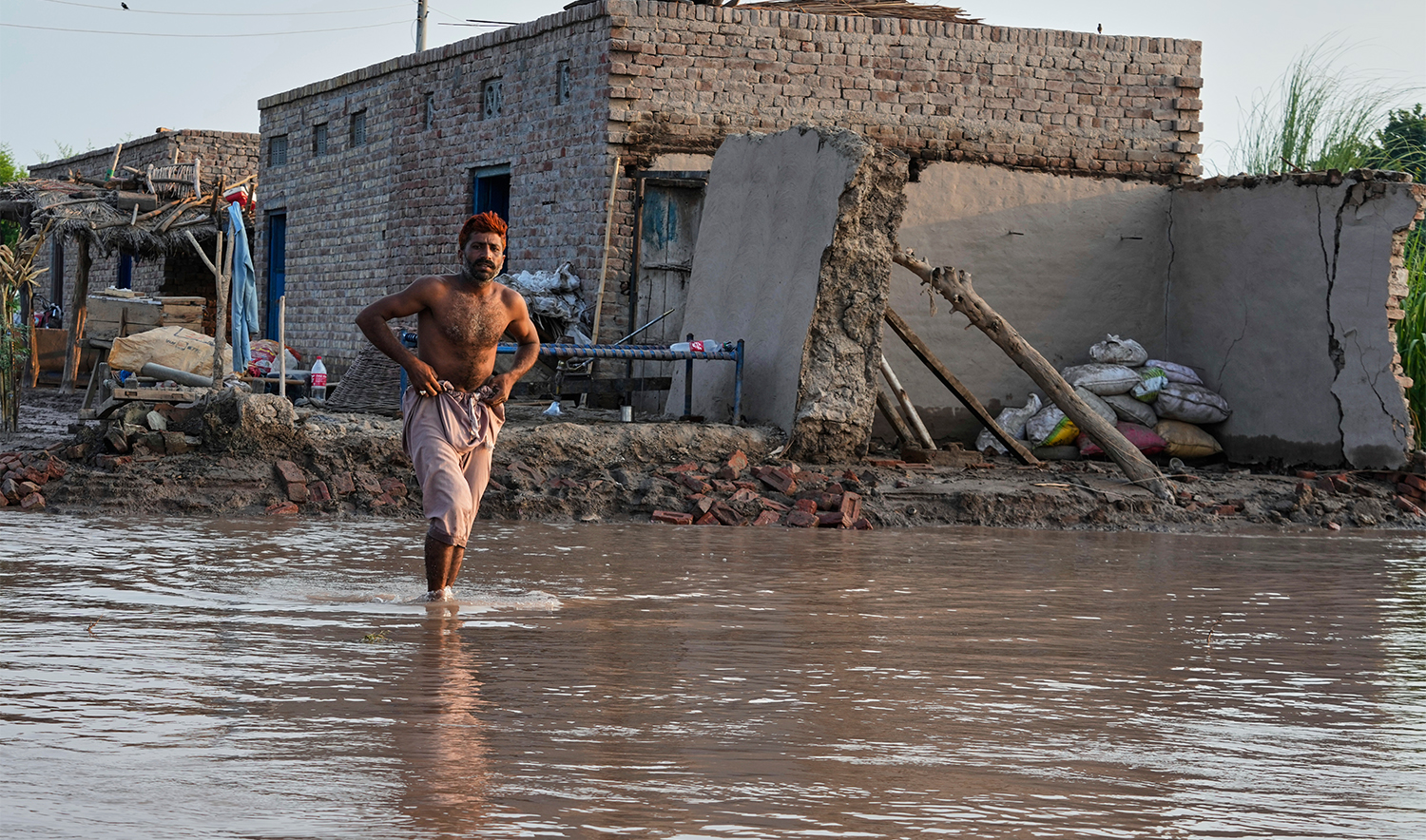 A villager walks toward a rescue workers boat approaching to providing food for his family at a flooded area in Maherian Wala, in Jhang district, Pakistan, on Sept. 1, 2025. (AP)