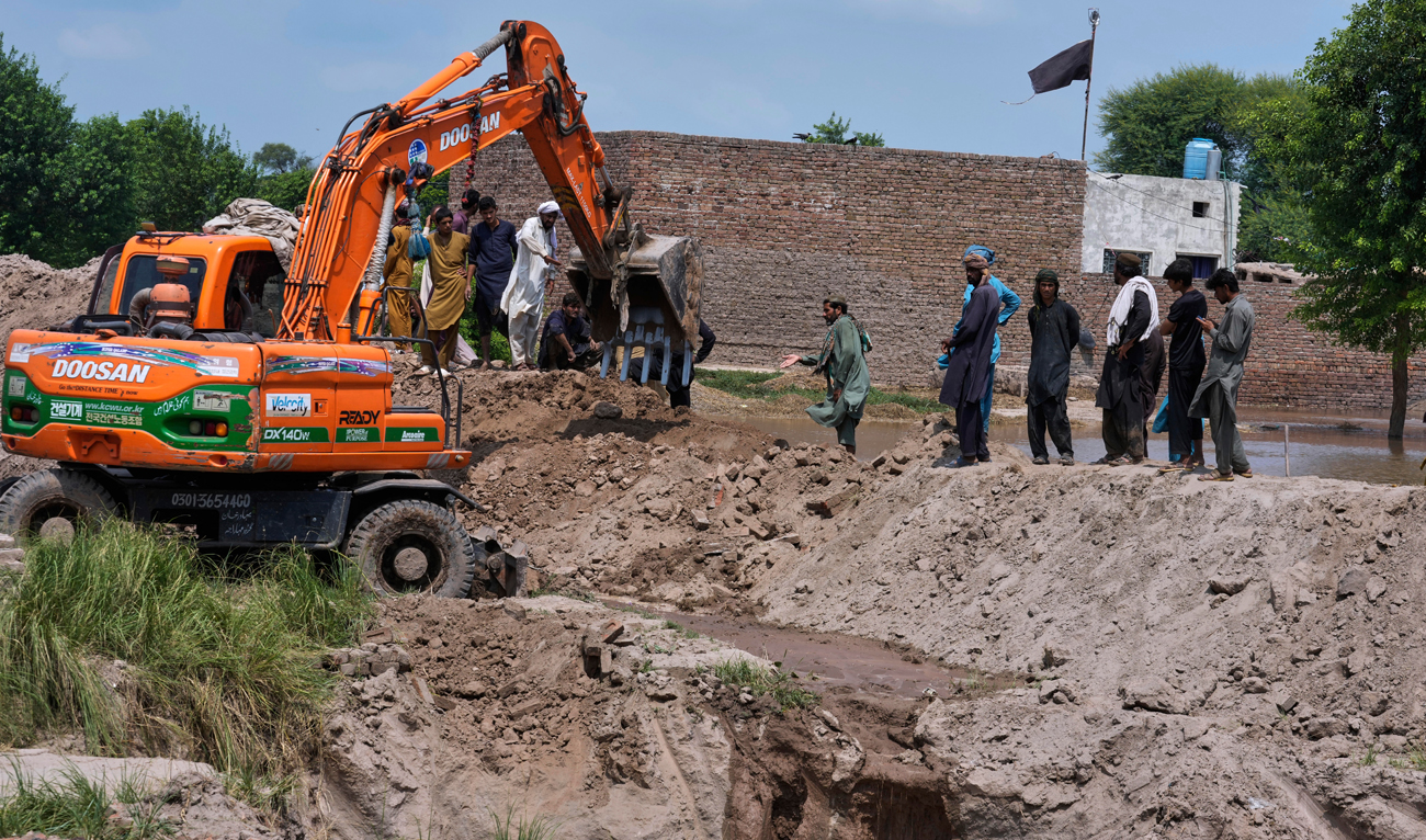 Residents use an excavator to build embankment following floodwater approaching their village in Garh Maharaja, in Jhang district, Pakistan on September 2, 2025. (AP)