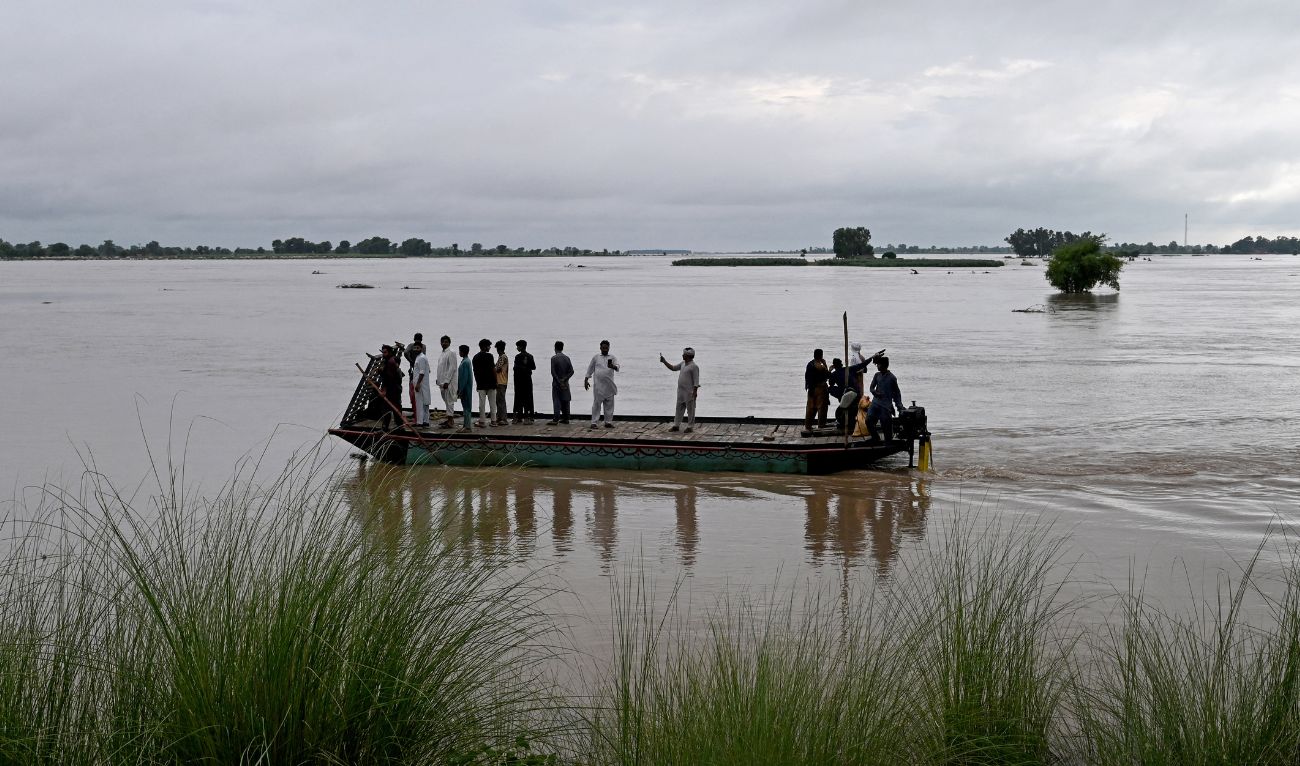 Villagers ferry a boat through floodwater to reach a safer place following heavy rain showers and rising water levels at a riverside village in Kasur district, Punjab province on August 31, 2025. (AFP)