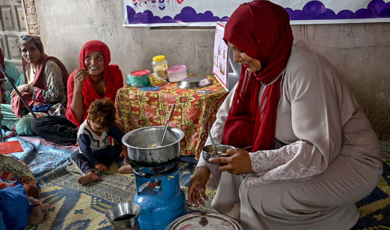This photograph taken on July 29, 2025 shows a female health worker (R) teaching mothers how to prepare nutritious meals for their children during a UNICEF nutrition programme at Fateh Muhammad Soomro village in the Sujawal district of Sindh province. (AFP)