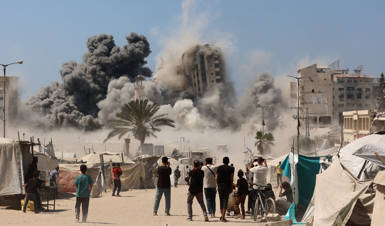 Palestinians wait and watch an explosion after Israel issued evacuation orders ahead of a military strike on the Mushtaha Tower (C) in Gaza City, on September 5, 2025, amid the war between Israel and the Hamas (AFP)