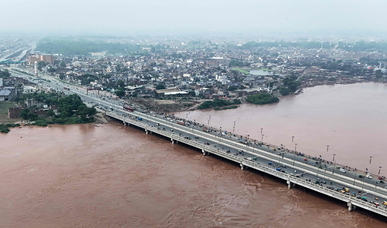 This aerial photograph shows commuters driving on a bridge as floodwaters flow through the Ravi river following a rise in water levels near residential areas in Shahdara, Lahore on August 29, 2025. (AFP)