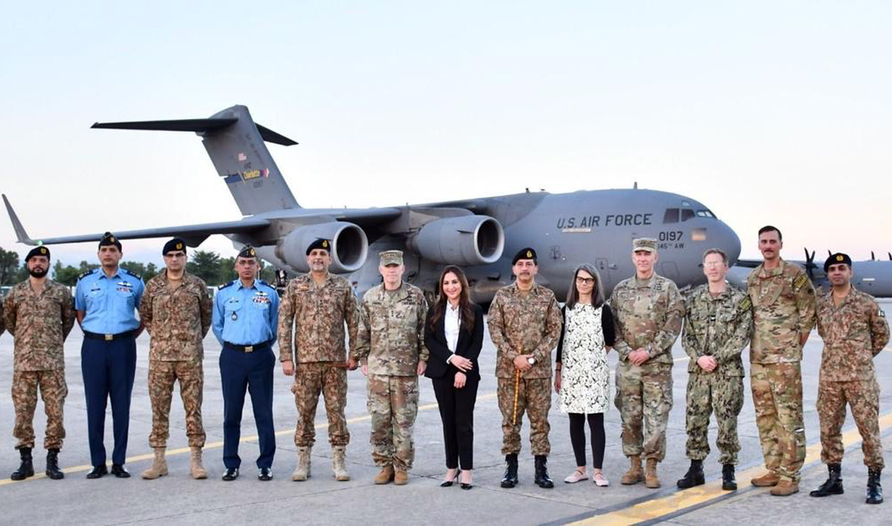 Natalie Baker (center), Chargé d’Affaires of US Embassy in Pakistan, along with other officials poses for a group photo while handing over emergency supplies for Pakistani flood affectees at Nur Khan Air Base in Rawalpindi. (@MohsinnaqviC42/X)