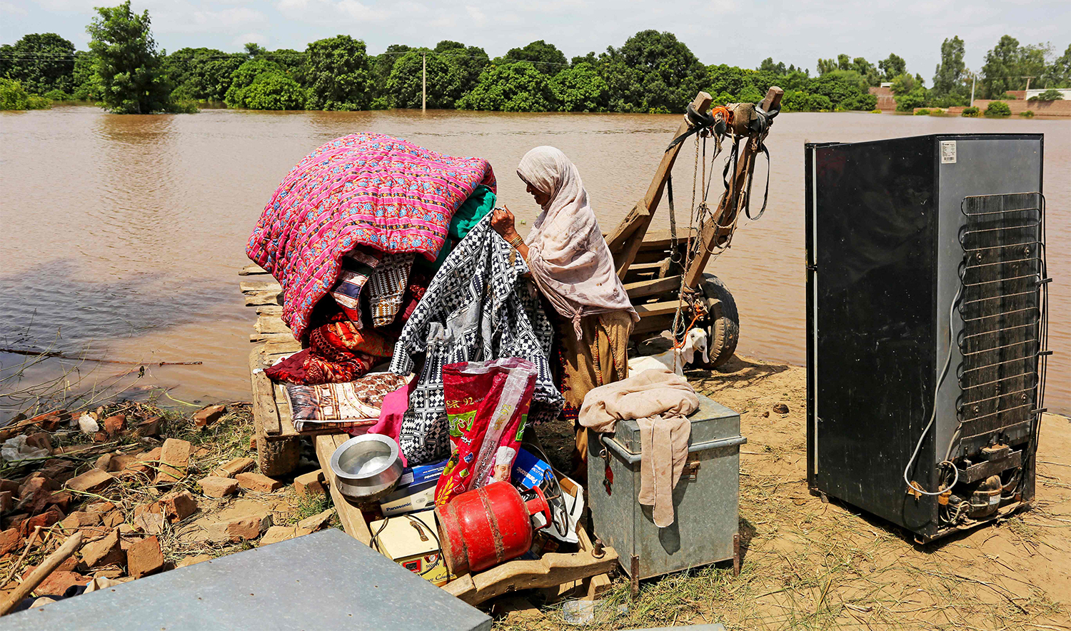 A flood-affected villager arranges her belongings whilst waiting to be evacuated from submerged home, after rains engorged river Sutlej, on the outskirts of Multan in Punjab province, on September 4, 2025. (AFP)