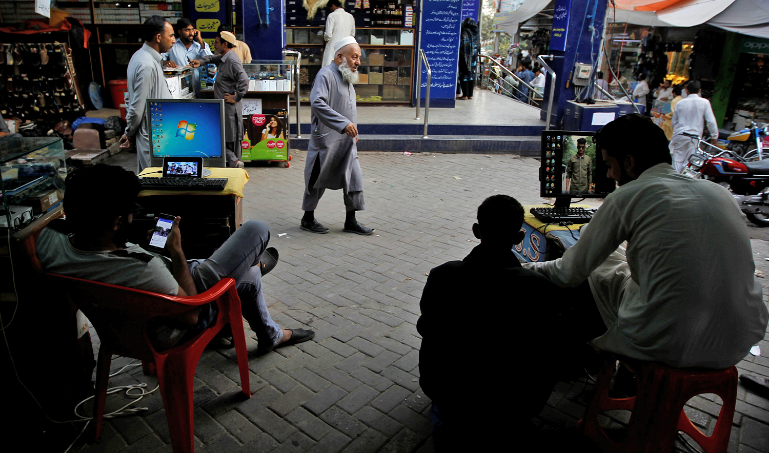 Men sit at their computers waiting to load media files into mobile phones for customers in the Abpara market in Islamabad, Pakistan, on October 20, 2017. (REUTERS/File)