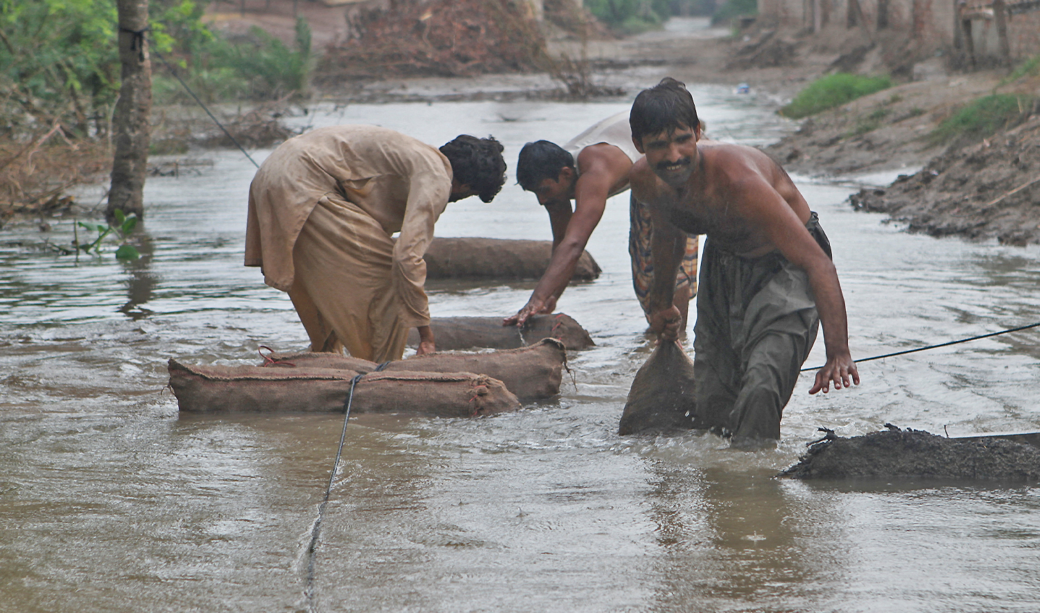 Farmers move sacks of taro root vegetable through a flooded street amid rain, following monsoon rains and rising water levels of the Chenab River, in Qasim Bela village on the outskirts of Multan, Punjab province, Pakistan, on September 7, 2025. (REUTERS)