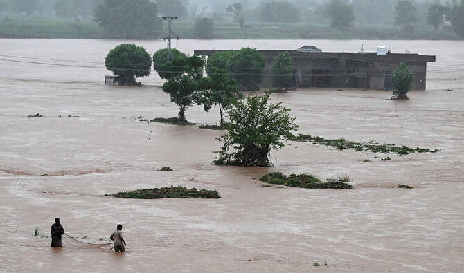 Local people catch fish in the floodwaters near a partially submerged house during heavy monsoon rains at the Ladian village of Rawalpindi on July 17, 2025. (AFP)