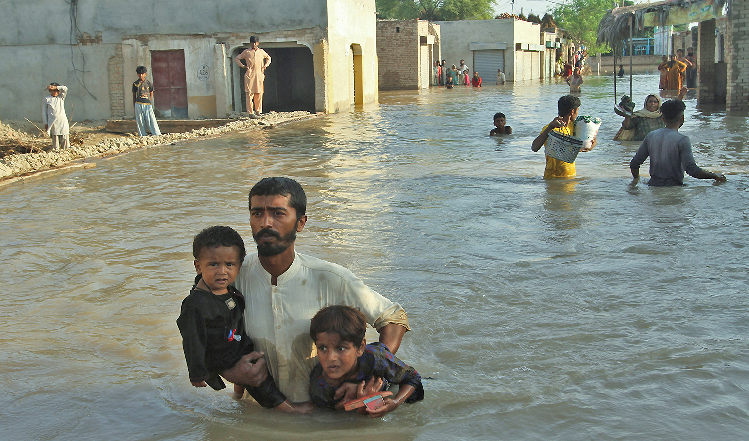Shafiullah, carries his children as he wades through a flooded street to catch a rescue boat during evacuations from the flooded area, following monsoon rains and rising water levels of the Chenab River, in Daryapur village on the outskirts of Jalalpur Pirwala, Punjab province, Pakistan, on September 9, 2025. (REUTERS)