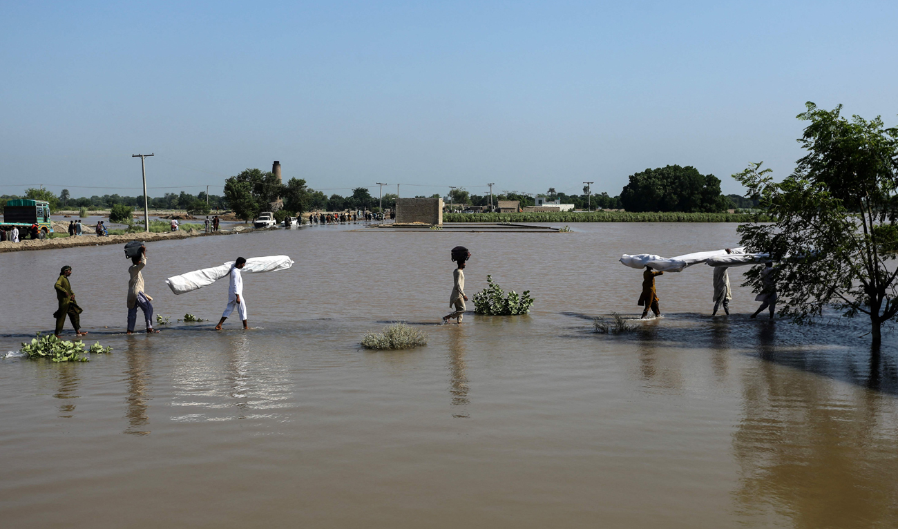 Flood-affected people carry makeshift tents as they wade through floodwaters at Alipur in the Muzaffargarh district of Punjab province on September 13, 2025, after the Head Panjnad, the confluence of five rivers Jhelum, Chenab, Ravi, Beas and Sutlej overflowed owing to heavy monsoon rains. (AFP)