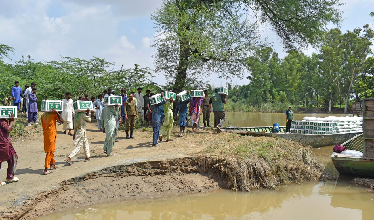 The handout photograph released by the King Salman Humanitarian Aid and Relief Center (KSrelief) on September 14, 2025, shows people carrying aid distributed in the flood-affected areas of Punjab, Pakistan. (KSrelief)