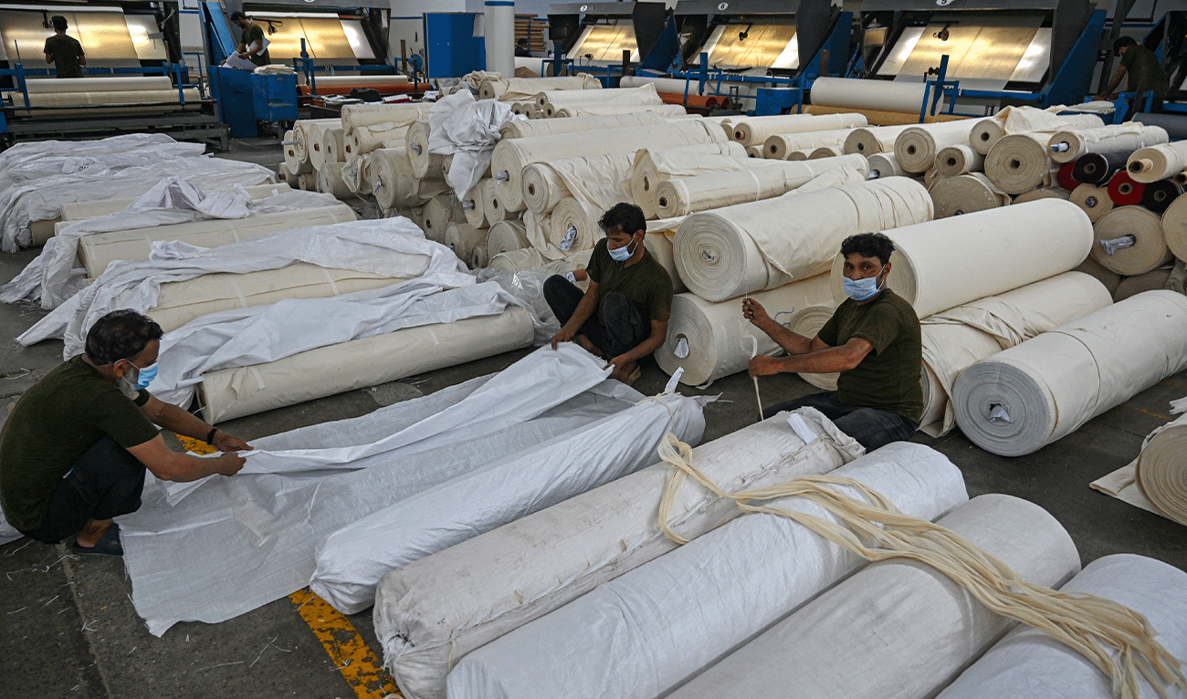 In this picture taken on July 20, 2023, workers pack fabric rolls at the Kohinoor Textile Mills in Lahore, Pakistan. (AFP/File)
