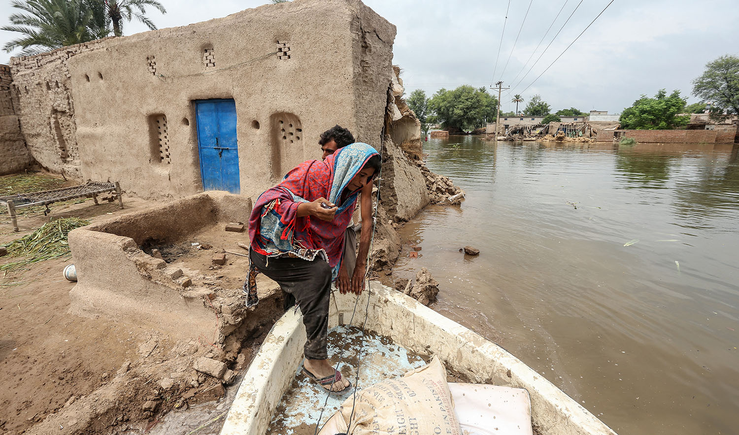 A flood-affected woman boards a boat as she evacuates her flooded house in Jalalpur Pirwala of the Multan district in Punjab province on September 8, 2025, after the Chenab River overflowed following heavy monsoon rains. (AFP)