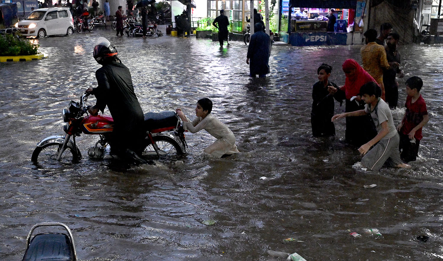 Commuters wade through a flooded street after heavy rainfall in Lahore on September 8, 2025. (AFP)