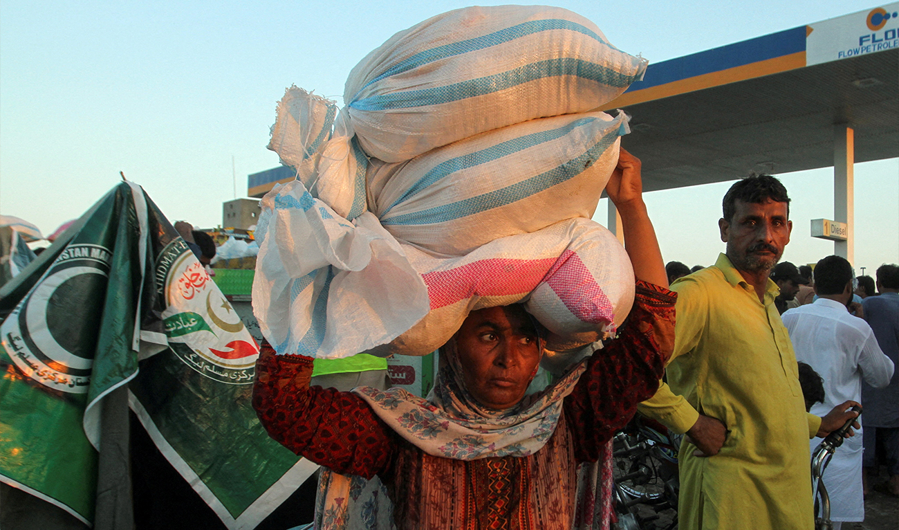 Zainab Bibi, a flood victim, carries sacks of handouts on her head, that she received from a distribution point, following monsoon rains and rising water levels of the Chenab River, in Alipur in Muzaffargarh District of Punjab province, Pakistan, on September 12, 2025. (REUTERS/File)