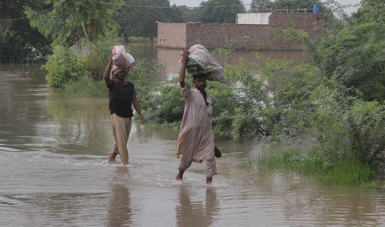 Residents carry their belongings as they wade through a flooded area, following monsoon rains and rising water levels of the Chenab River, in Muzaffargarh district of Punjab province, Pakistan, on September 6, 2025. (REUTERS/File)