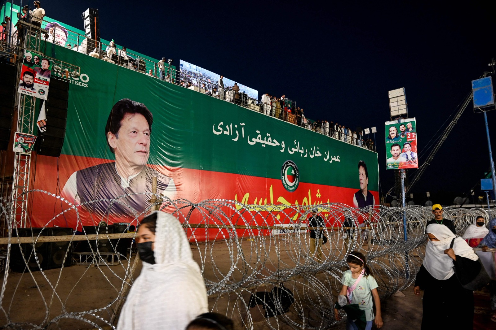 Supporters of Pakistan Tehreek-e-Insaf (PTI) party walk past a banner of their leader and jailed former Prime Minister Imran Khan during a protest demanding his release in Peshawar on September 27, 2025. (AFP)