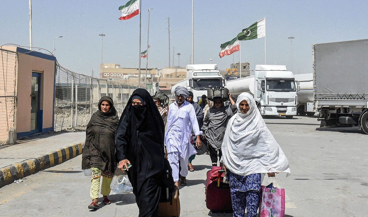Pakistani Shiite pilgrims carrying their belongings walk across the Pakistan-Iran border after returning from Iran in Taftan, in Balochistan province, on June 19, 2025. (AFP/File)