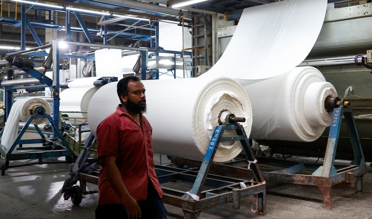 A worker walks at the bleaching unit with the cotton fabric rolls in the background, at the textiles manufacturer of the Liberty Mills Limited in Karachi, Pakistan, on August 2, 2025. (REUTERS/File)