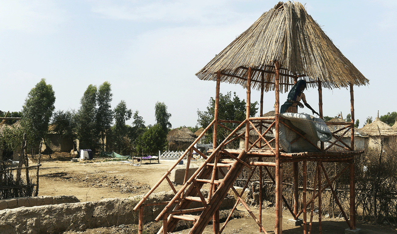 In this picture taken on April 9, 2023, a girl places a mattress for drying at an elevated bamboo structure in Pono Colony at Sanjar Chang village, in Tando Allahyar district. (AFP/File)