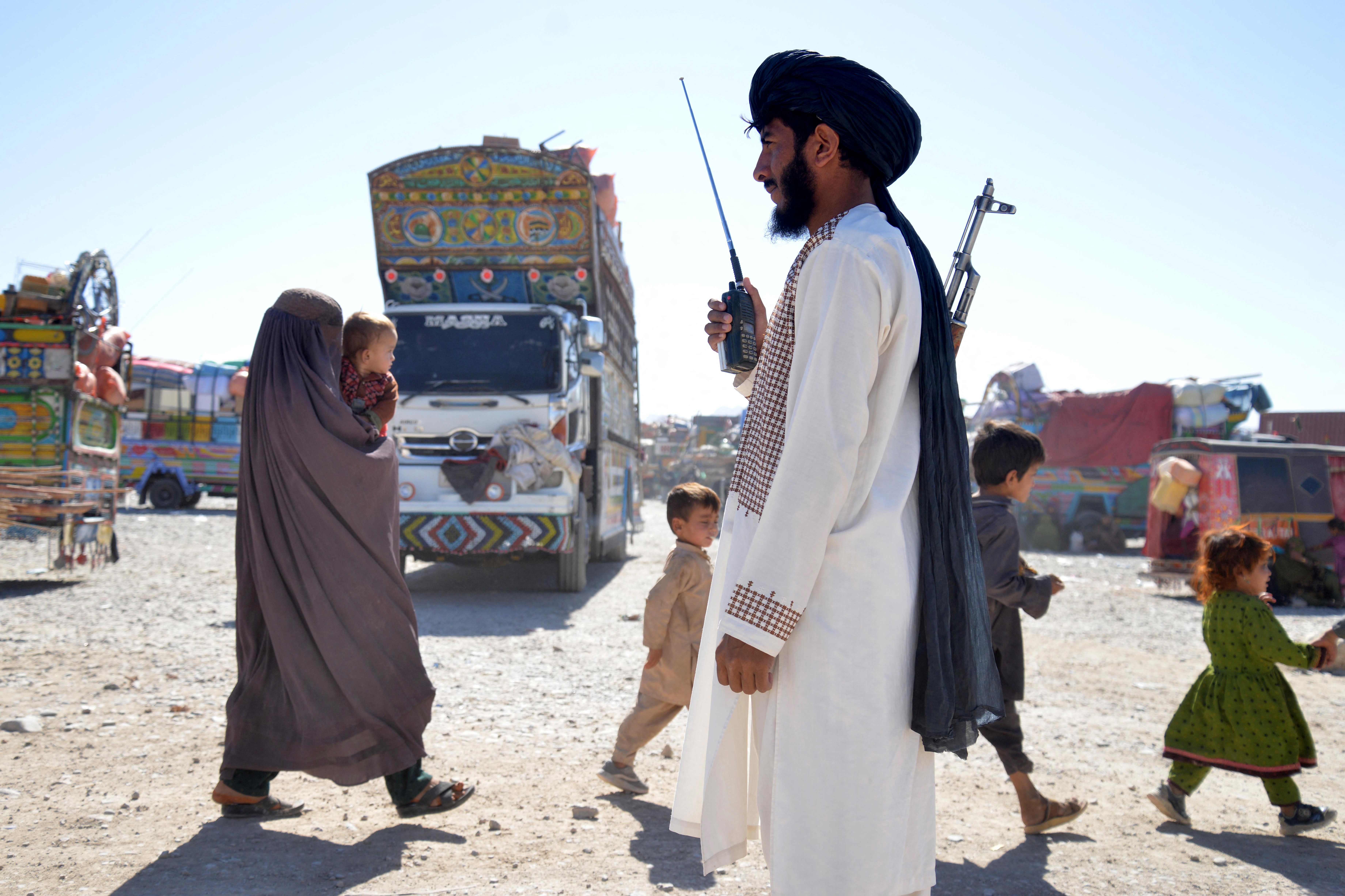 Taliban security personnel stands guard as Afghans deported from Pakistan arrive at a registration centre at Takhta Pul in Kandahar province on October 9, 2025. (AFP)