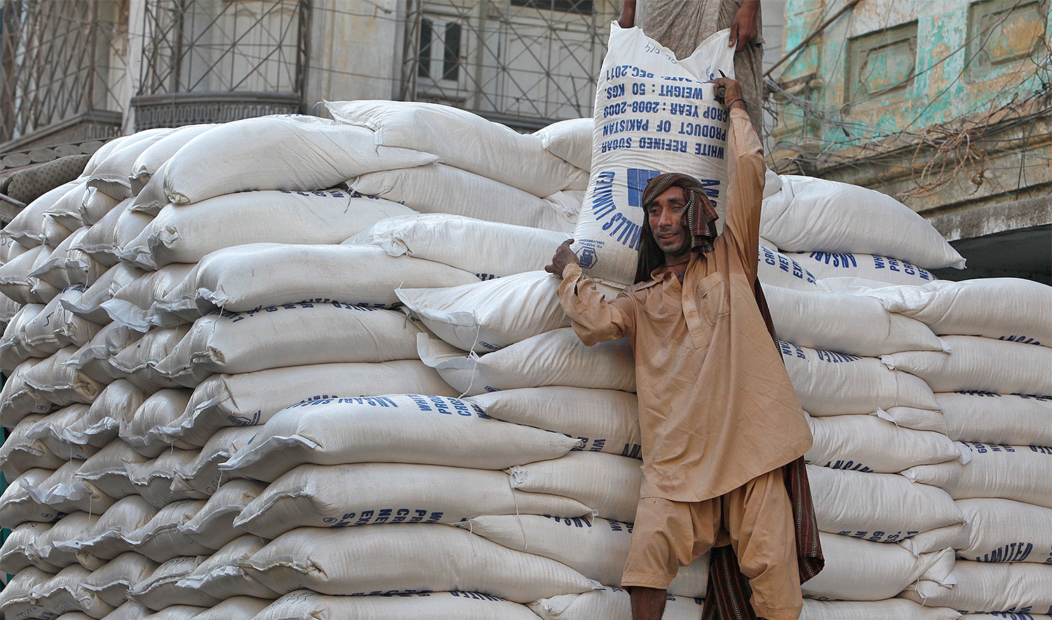 A laborer unloads bags of sugar from a delivery truck to a market in Karachi October 15, 2009. (REUTERS/File)
