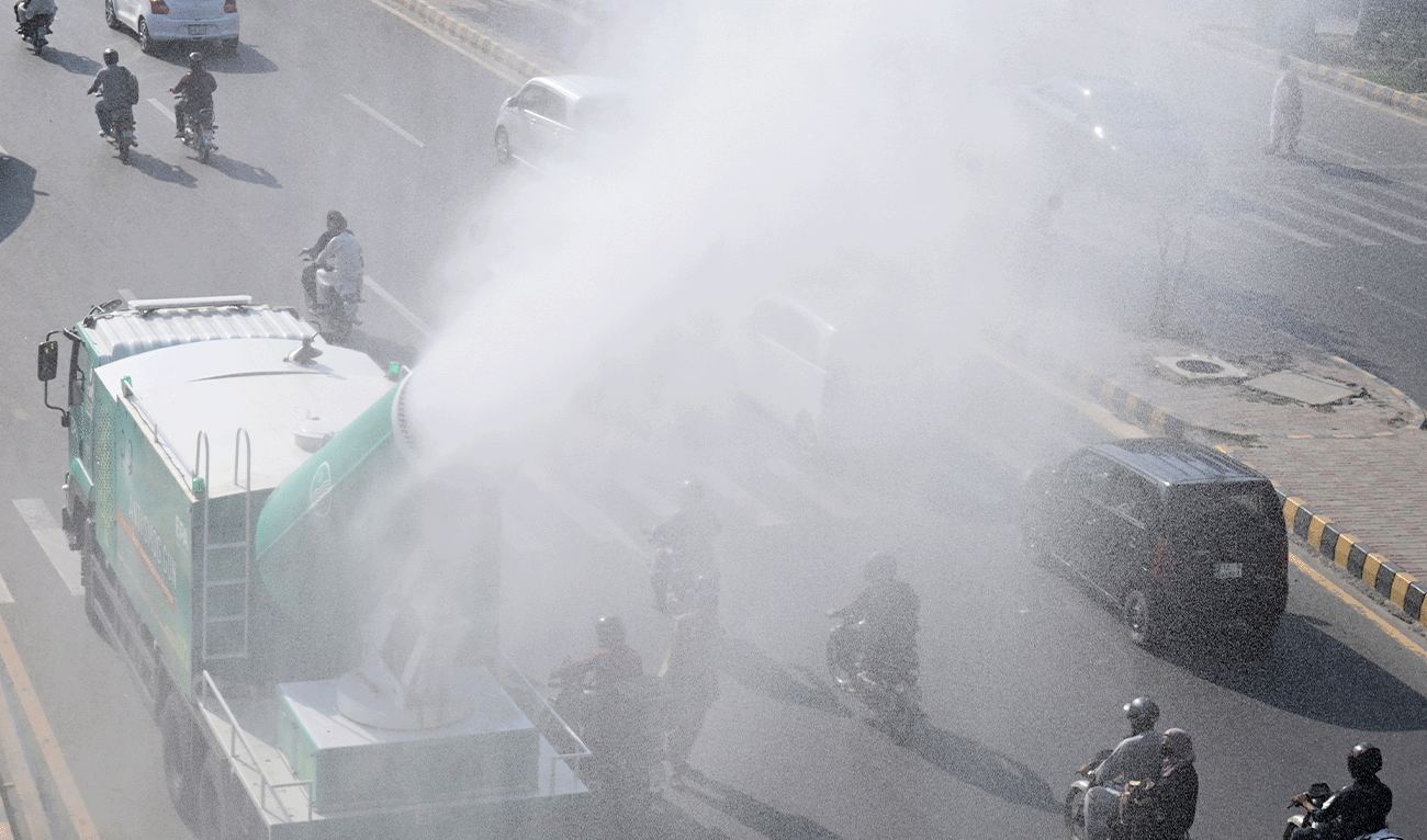 Workers spray water from an anti-smog gun along a road, to reduce pollution in Lahore on October 16, 2025. (AFP/File)