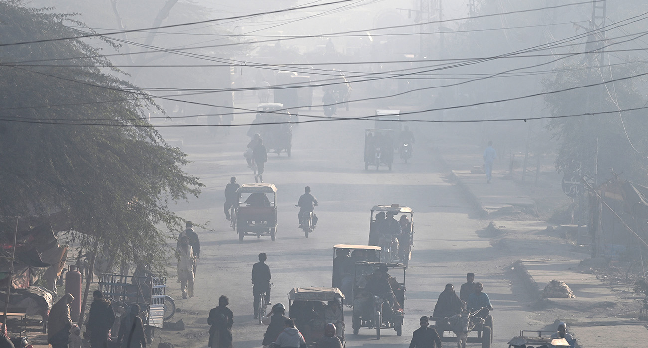 Commuters ride along a street amid dense smog in Lahore on December 5, 2024. (AFP)