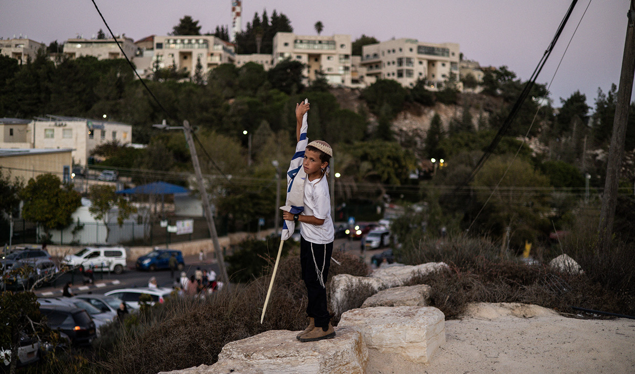 A young Israeli settler holds a flag during the return of freed hostage Avinatan Or in the Israeli settlement of Shiloh in the occupied West Bank on October 21, 2025. (AFP)