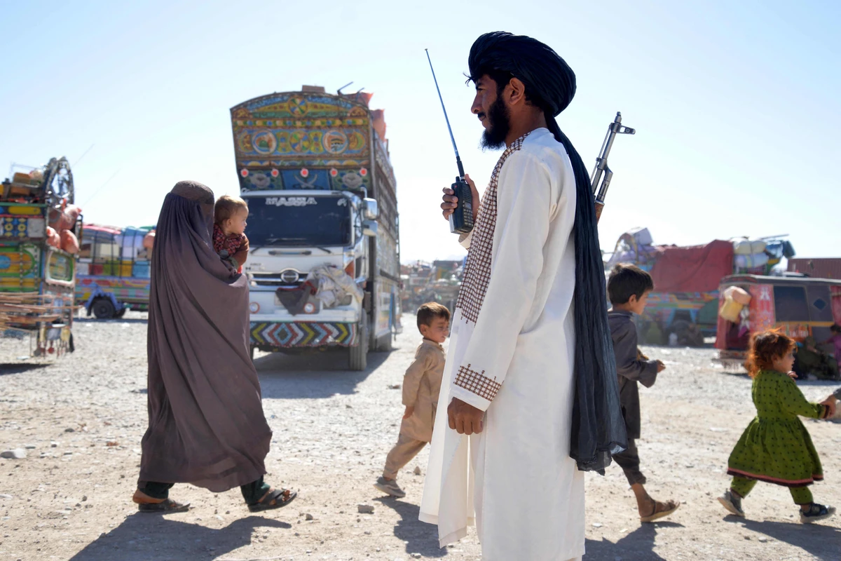 Taliban security personnel stands guard as Afghans deported from Pakistan arrive at a registration centre at Takhta Pul in Kandahar province on October 9, 2025. (AFP)