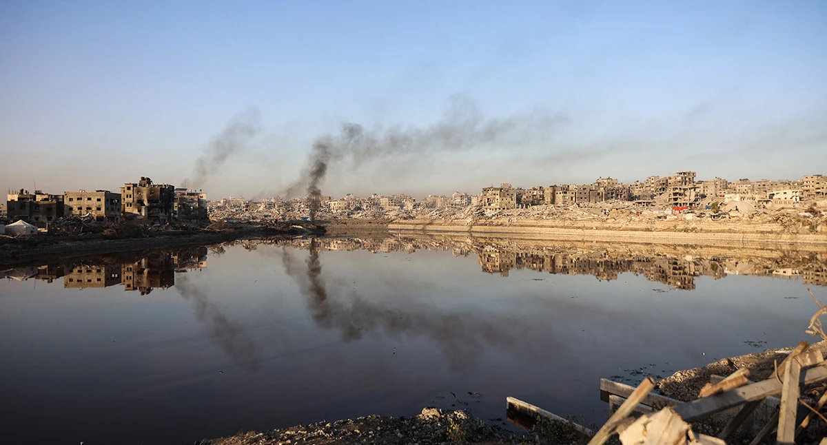 Heavily damaged buildings are reflected in a water basin in the Sheikh Radwan neighborhood of Gaza City on October 22, 2025. (AFP/ file)