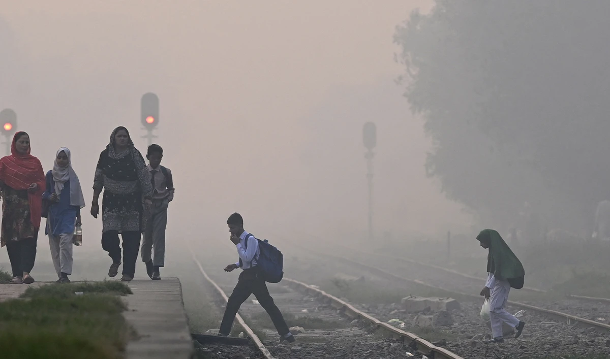 School children walk across a railway track amid dense smog in Lahore, Pakistan, on October 29, 2025. (AFP)