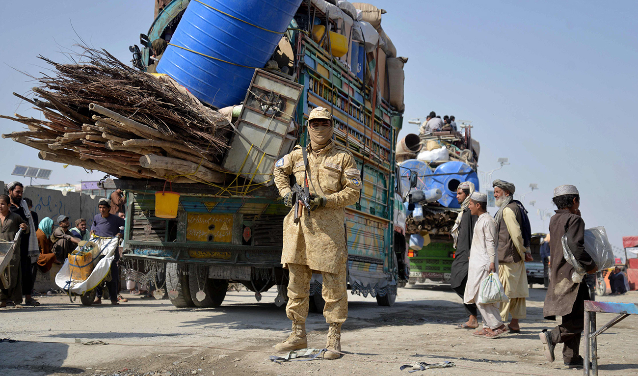 A Taliban security personnel stands guard as deported Afghan refugees from Pakistan arrive at the zero-point border crossing between Afghanistan and Pakistan, in the Spin Boldak district of Kandahar province on October 27, 2025. (AFP)