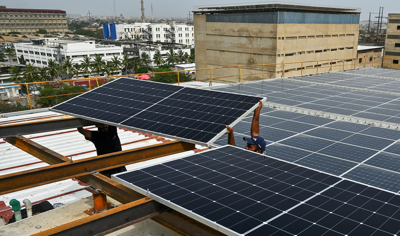 In this photograph taken on July 2, 2025, technicians install solar panels on the rooftop of a factory in Pakistan's port city of Karachi. (AFP)