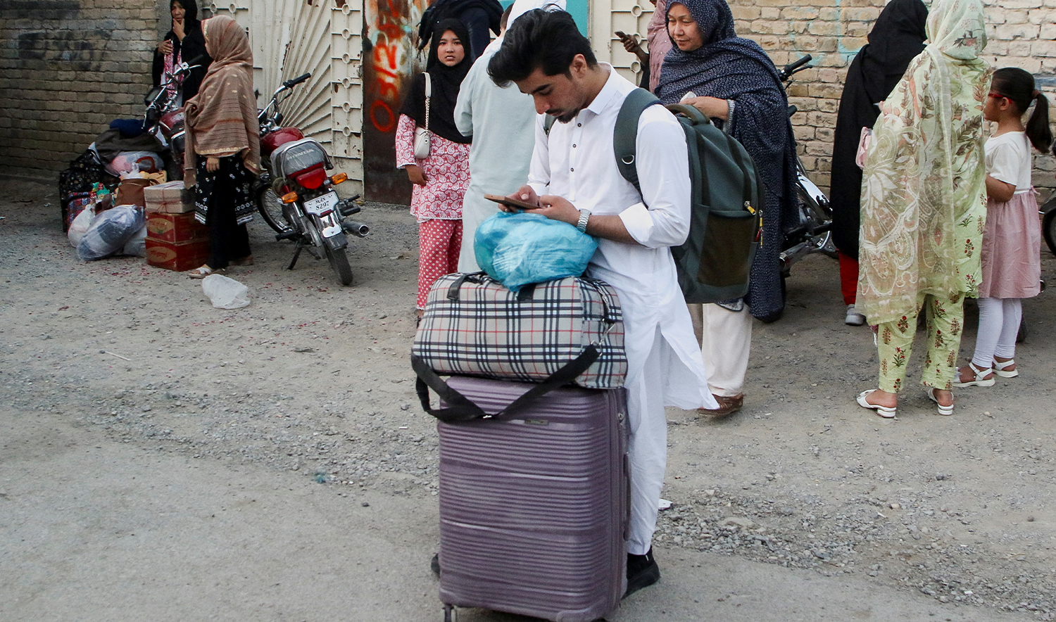 A Pakistani student uses his mobile phone as he stands with his belongings in Quetta, Pakistan, on June 17, 2025. (REUTERS/File)