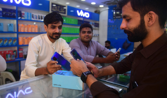 A shopkeeper shows a mobile phone to a customer at a mobile phone store in Karachi on May 20, 2022. (AFP/File)