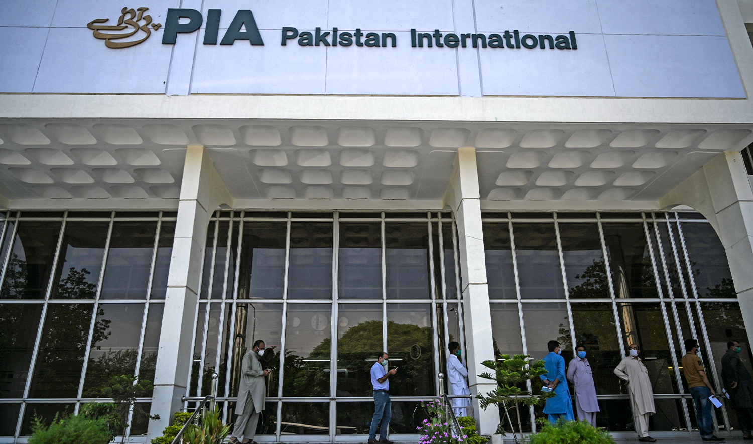People stand in queue as they wait their turn to buy flight tickets outside Pakistan International Airlines (PIA) office in Islamabad on July 1, 2020. (AFP/File)