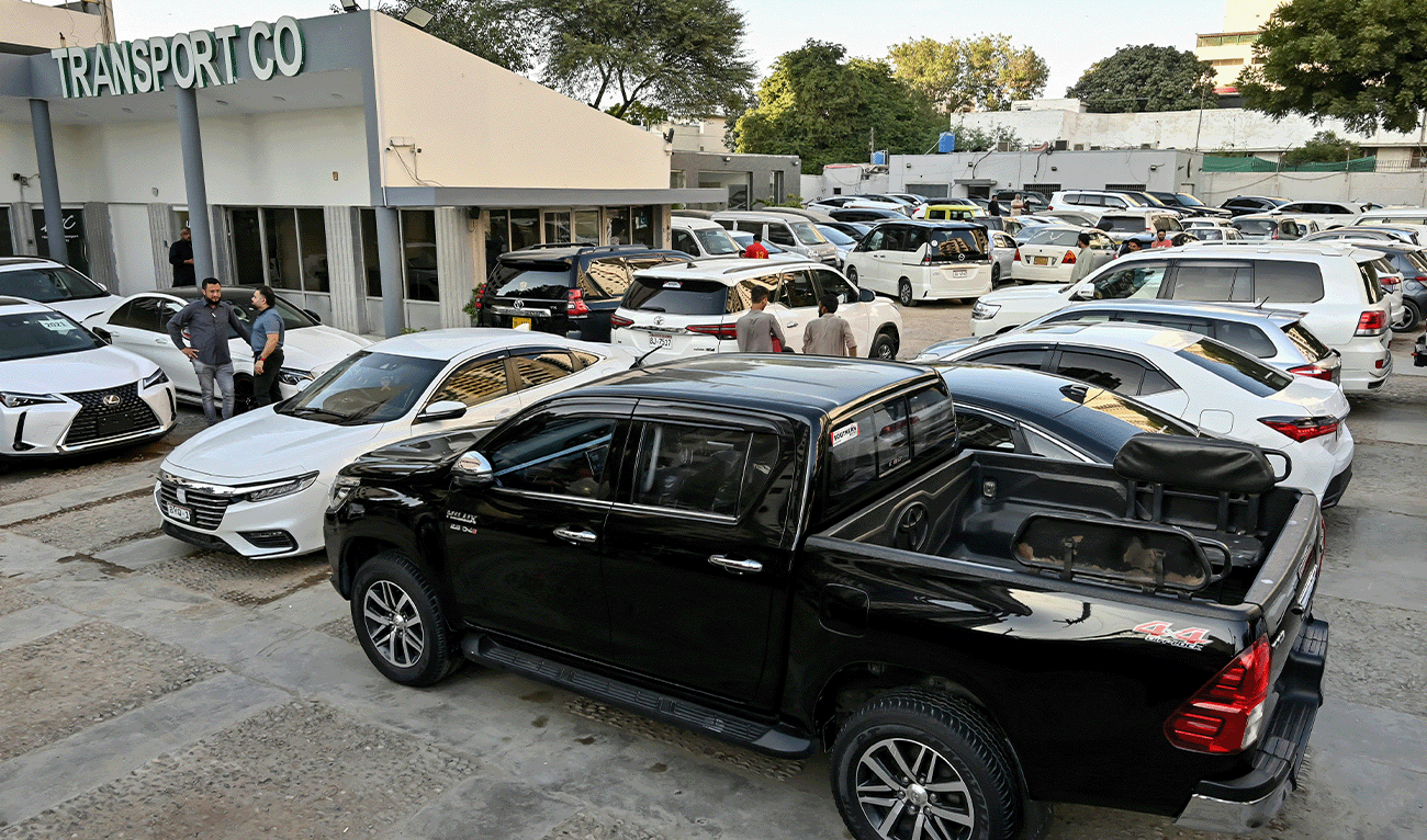 This photograph taken on November 11, 2024 shows car dealer Fahad Nazir (second-left) speaking to a customer near a Toyota Hilux pick-up truck parked at his showroom yard in Karachi, Pakistan. (AFP/File)